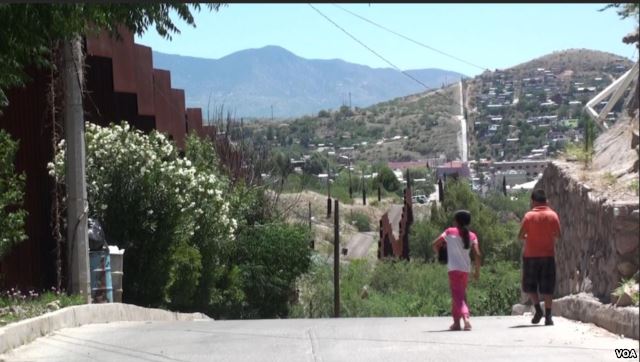 Two kids by the border wall in Nogales, Mexico. (G. Flakus:VOA)